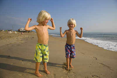Twins Showing Muscles on Beach